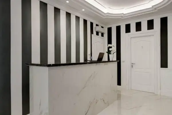 Interno della reception del Boutique Hotel SM Vatican Relais con bancone in marmo e pareti a righe verticali