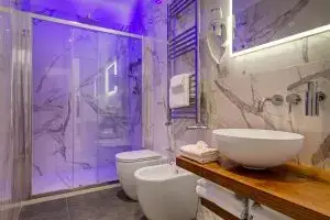 Bagno del Boutique Hotel SM Vatican Relais con doccia illuminata, bidet, lavabo e rivestimenti in marmo