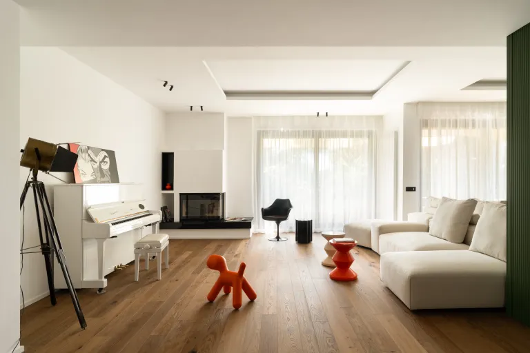 Ampio soggiorno moderno con pavimento in parquet di legno naturale, pianoforte bianco e arredi di design contemporaneo, progetto d'interni Funaro Home.