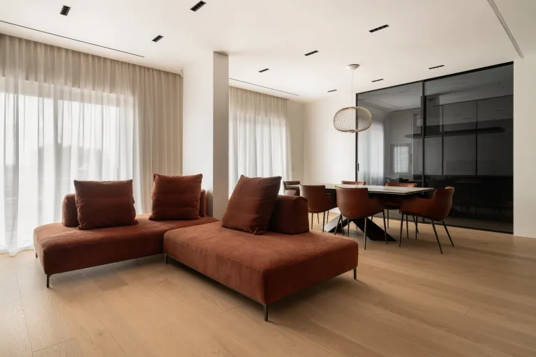 Soggiorno moderno con pavimento in parquet di rovere chiaro a grandi plance, divano color ruggine e zona pranzo, progetto d'arredo Funaro Home.