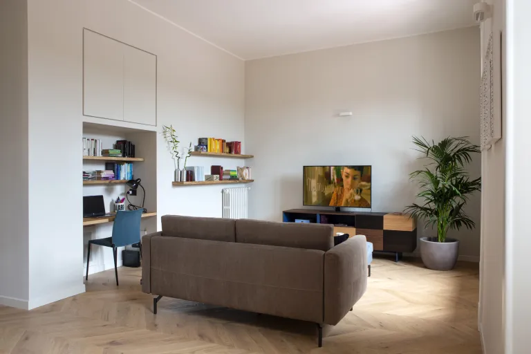 Soggiorno moderno con pavimento in parquet a spina di pesce in rovere chiaro, divano marrone e angolo studio integrato, arredamento d'interni Funaro Home.