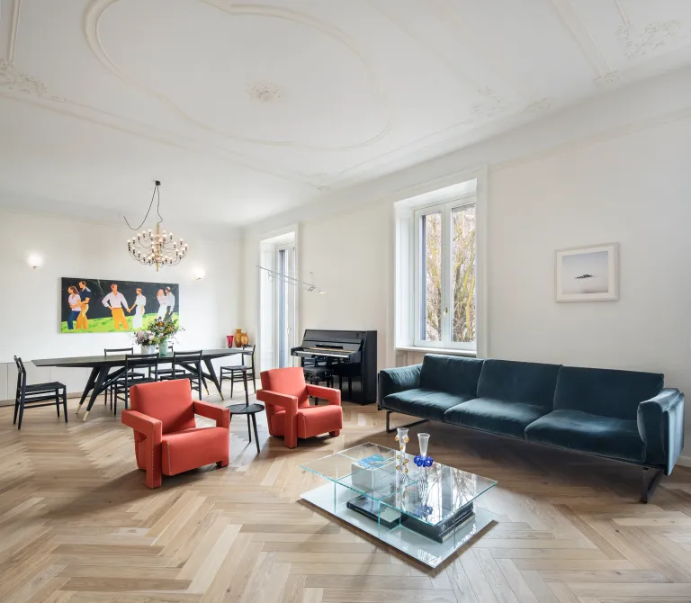 Soggiorno elegante con pavimento in parquet a spina di pesce in rovere, soffitti alti con stucchi decorativi, divano in velluto e arredi di design Funaro Home.