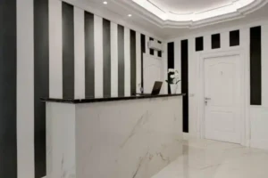 Interno della reception del Boutique Hotel SM Vatican Relais con bancone in marmo e pareti a righe verticali